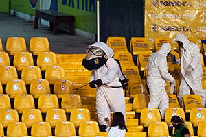 The stands at an empty Universitario Stadium is disinfected during halftime of the Mexican Apertura 2020 football tournament match between Tigres and Guadalajara in Monterrey, Mexico, on September 5, 2020. The worker on the left wears the mask of the Tigres’ mascot. (AFP)